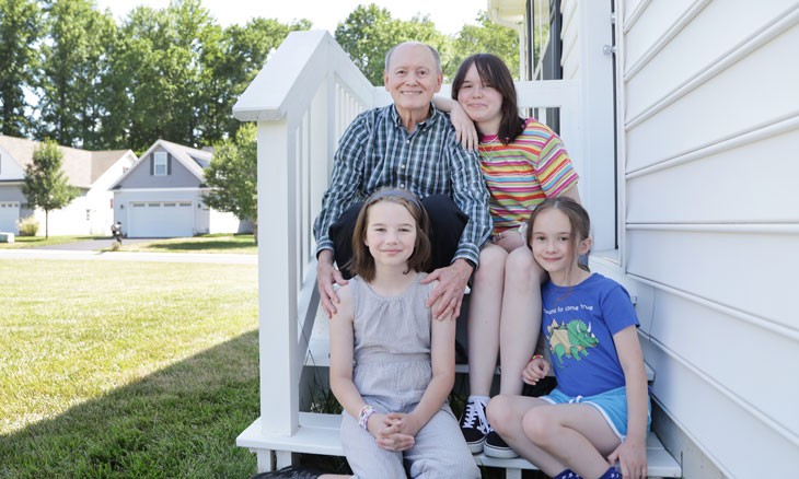 Patient Ed Eison sitting on his back porch with his three granddaughters